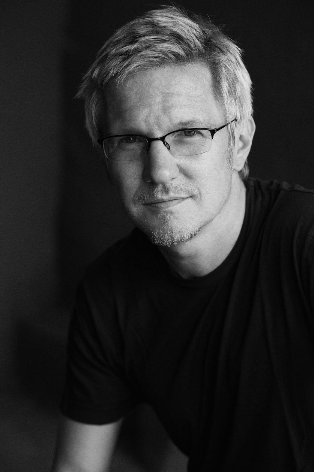 Black-and-white portrait of Paul Haslinger against a dark background.
